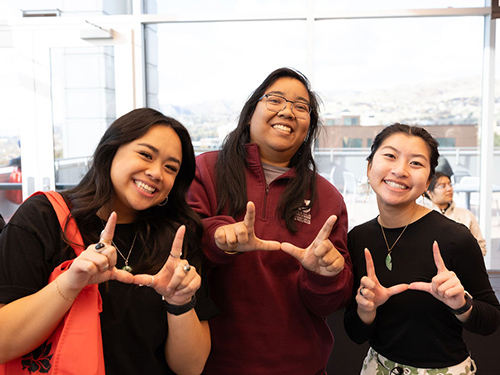 three students flashing the u with their hands